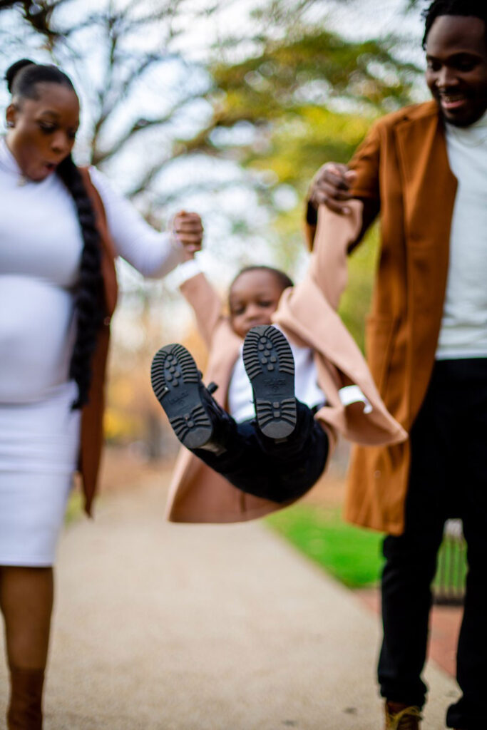 stylish and fun family portrait of parents swinging their son