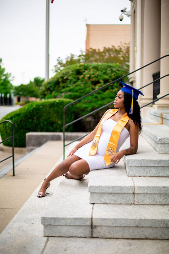 black girl sitting on stairs cap and gown photos in greenville nc