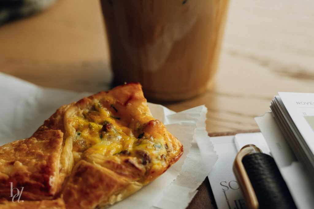 bacon egg and cheese croissant beside iced latte and planner