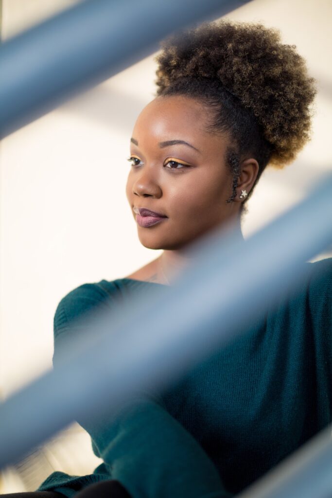 Unique lifestyle headshot post of an african american woman wearing a green sweater in Greenville NC