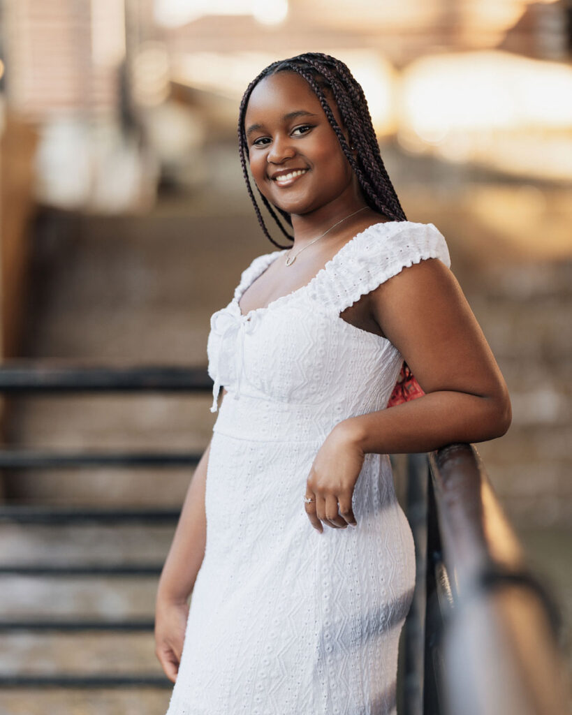 Smiling high school senior in white dress at Durham's American Tobacco Campus