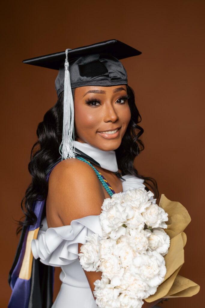 Graduate posing with white roses for ECU photos