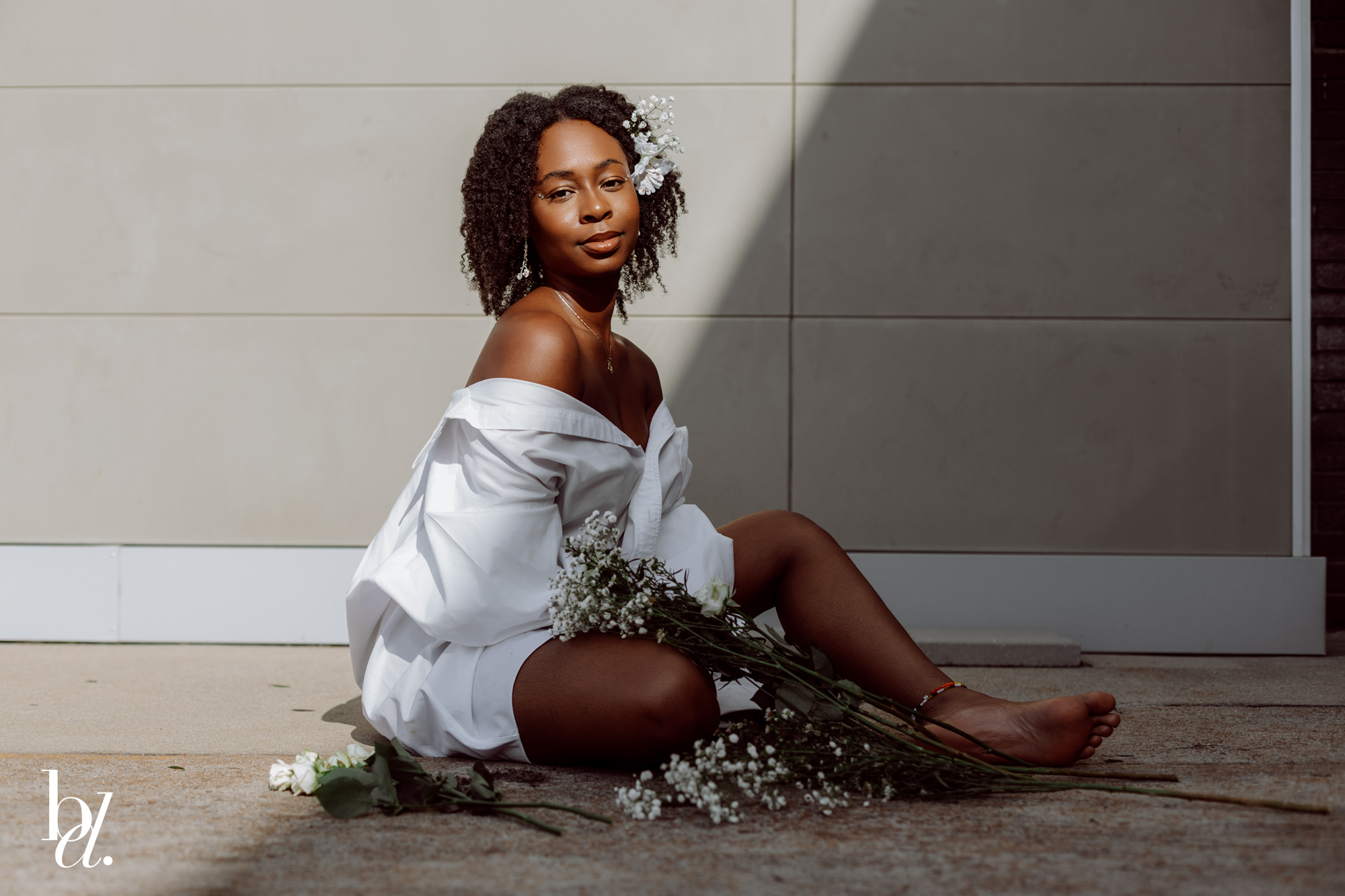 Editorial portrait of black girl in white oversized shirt against neutral wall