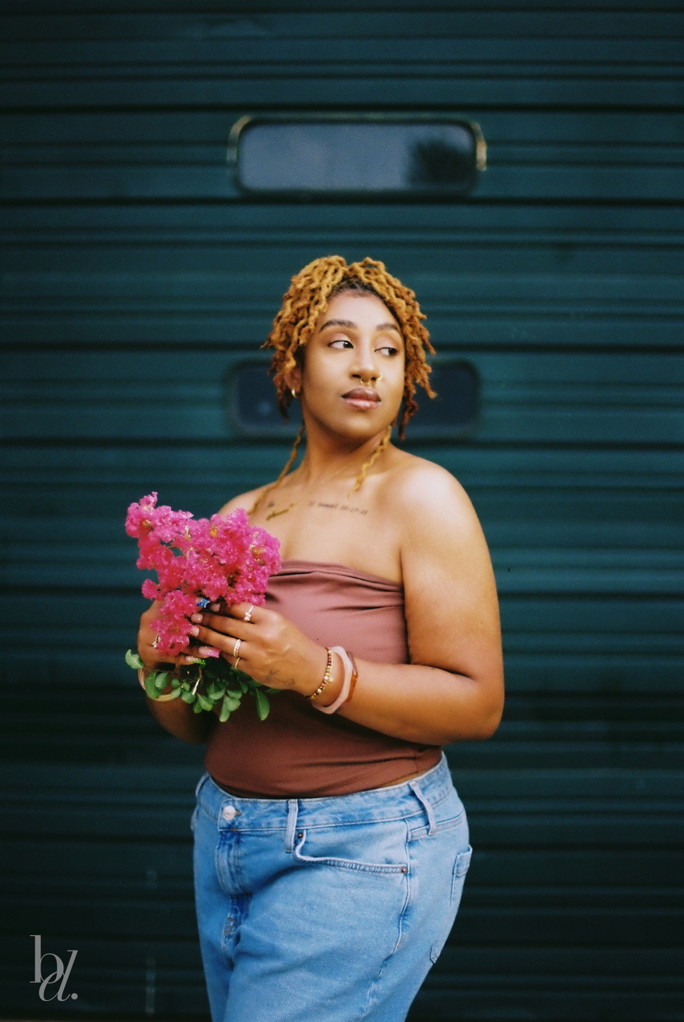 Portrait of a woman standing in front of a green garage door in downtown Raleigh, shot on Kodak Gold 200