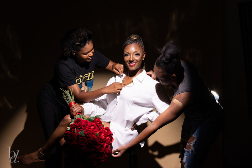black woman getting help from friends during spotlight studio birthday photoshoot in raleigh nc