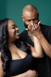 Bride smiling as groom kisses her hand during just married studio photo session