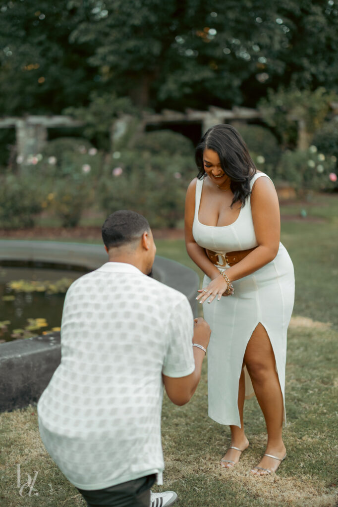 Close-up of hands as an engagement ring is placed on a finger during a Rose Garden proposal in Raleigh.