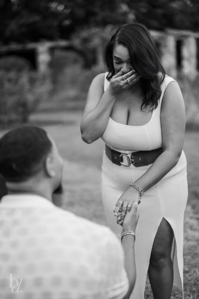 Black-and-white image capturing an emotional reaction during a surprise proposal in the Raleigh Rose Garden.
