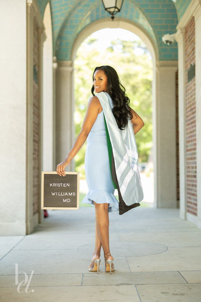 UNC doctoral graduate holding name sign at the Bell Tower