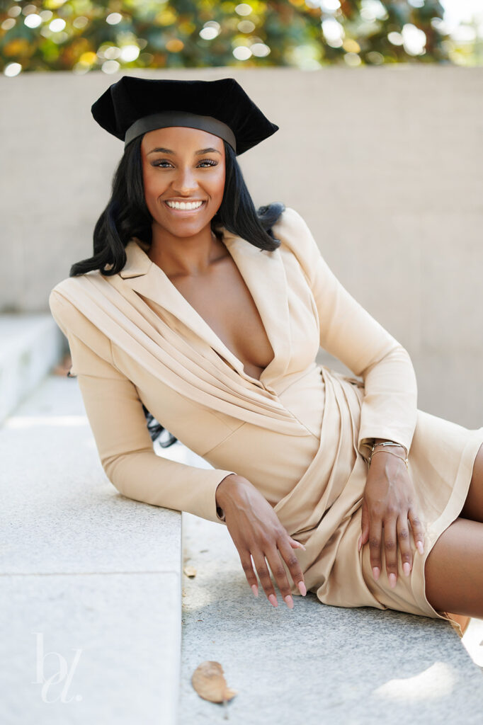 smiling doctoral graduate portrait in beige dress outdoor campus setting at UNC Wilson Library