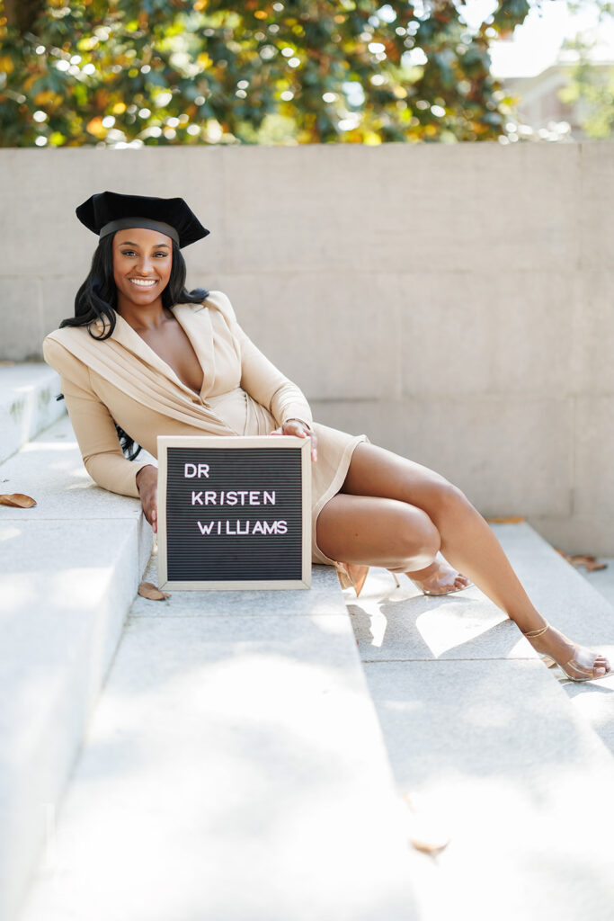 graduate holding custom name sign prop during UNC graduation photos on Wilson Library steps