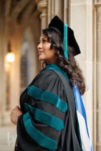 Duke DPT graduate in doctoral regalia posing in Duke Chapel archway