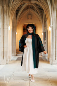 Duke doctoral graduate walking through Duke Chapel corridor in regalia