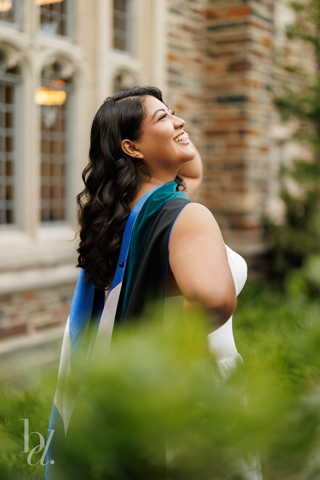 Close portrait of Duke doctoral graduate smiling in regalia outside Duke Chapel
