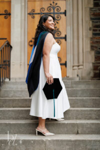 Doctoral graduate standing on Duke Chapel stairs holding graduation cap