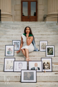 UNC School of Medicine graduate posing with framed ancestor photos during doctoral graduation session