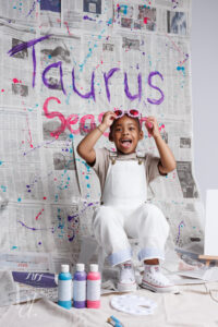 Child smiling with playful glasses during a colorful paint splash birthday photo session in Raleigh