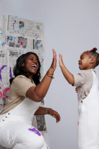 Mother and daughter sharing a high five during a fun paint splash photo shoot