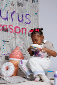 Child eating birthday cake during a colorful paint splash birthday photo session