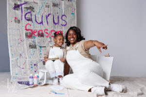 Mother and daughter sitting together during a playful Raleigh birthday photos session with cake and paint