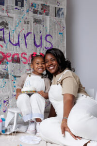 Mother and daughter smiling together in front of a colorful paint splash birthday backdrop