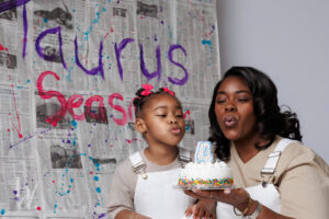 Mother and daughter blowing out a birthday candle during a paint themed birthday photo session
