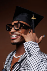 Close-up editorial graduation portrait of a graduate showing silver grill in cap and blazer.