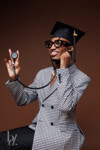 Graduate smiling while holding a stethoscope during a Raleigh studio graduation session.