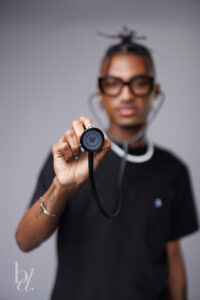 Close-up of a stethoscope held toward the camera during a creative studio graduation portrait.